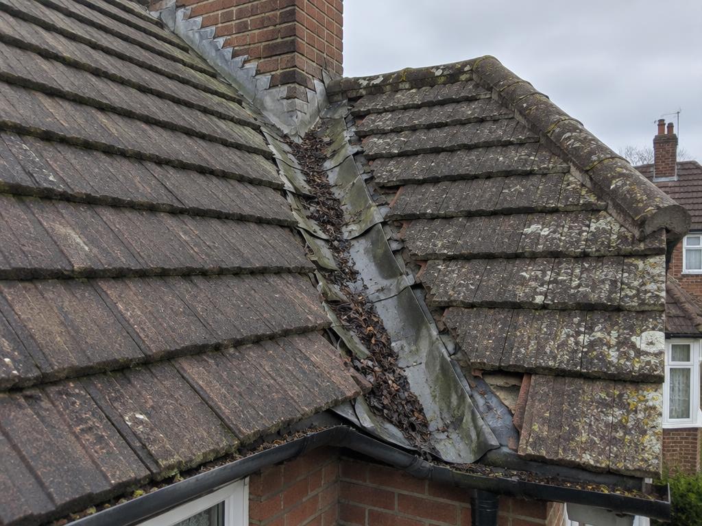 Illustrative example: blocked roof valley with debris and a distorted lead valley lining between two tiled pitches